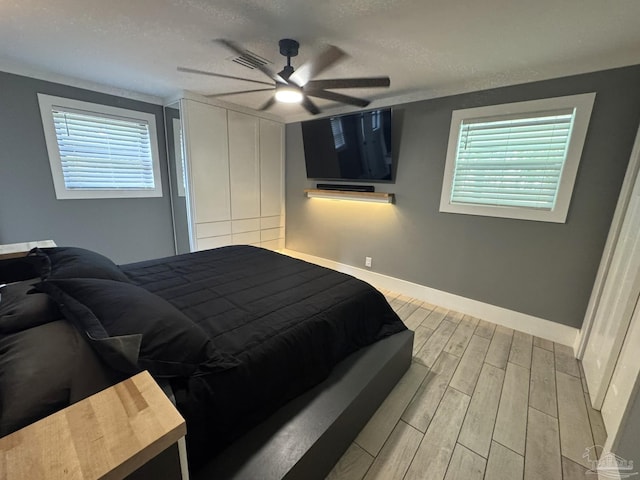 bedroom featuring a closet, multiple windows, baseboards, and wood finish floors