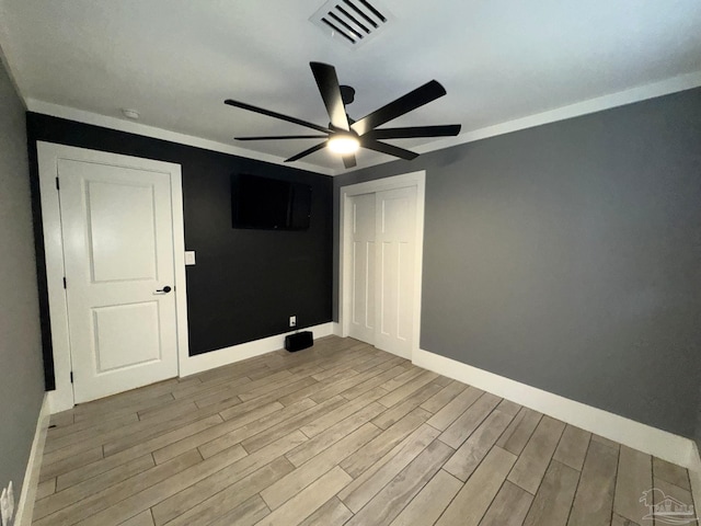 empty room with wood finished floors, ceiling fan, baseboards, and visible vents