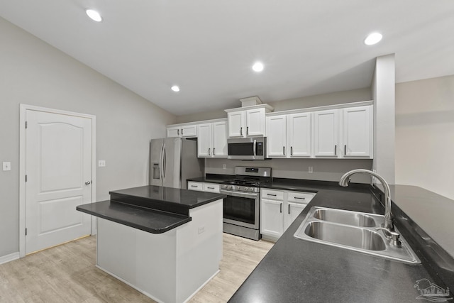 kitchen featuring dark countertops, light wood-style flooring, appliances with stainless steel finishes, white cabinetry, and a sink