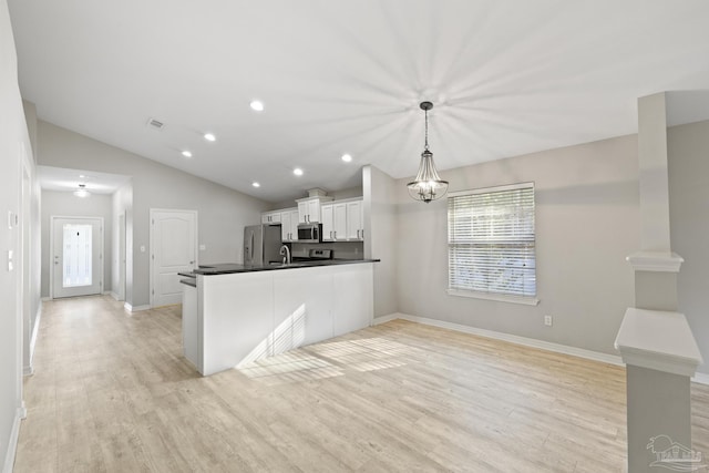 kitchen with light wood-style flooring, dark countertops, stainless steel appliances, white cabinets, and vaulted ceiling