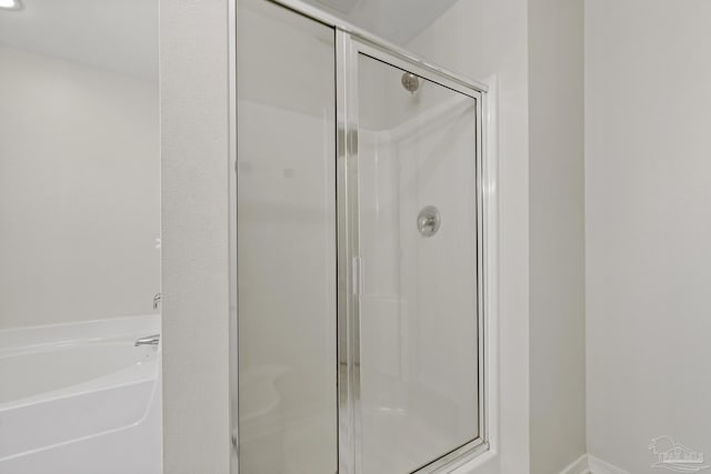 bathroom featuring a bath and a shower stall