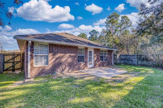 back of property with a lawn, a gate, a fenced backyard, brick siding, and a patio area