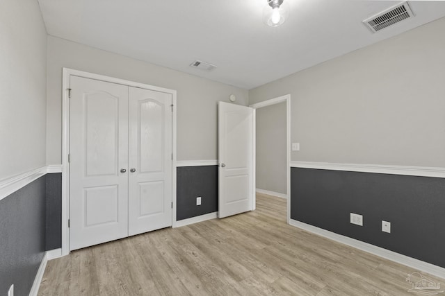 unfurnished bedroom with wood finished floors, visible vents, and baseboards