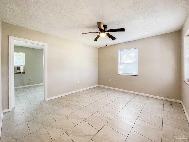 empty room with light tile patterned flooring, ceiling fan, a textured ceiling, and baseboards