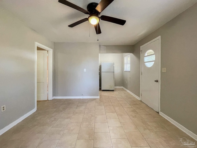 interior space with light tile patterned floors, a ceiling fan, and baseboards