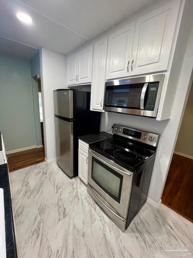 kitchen with light hardwood / wood-style flooring, appliances with stainless steel finishes, and white cabinets