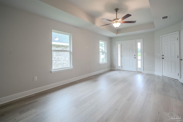 foyer featuring visible vents, a tray ceiling, wood finished floors, baseboards, and ceiling fan