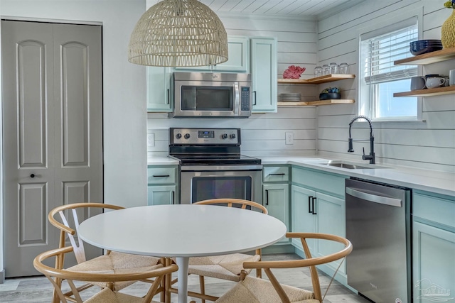 kitchen featuring sink, appliances with stainless steel finishes, light hardwood / wood-style flooring, wooden walls, and decorative backsplash