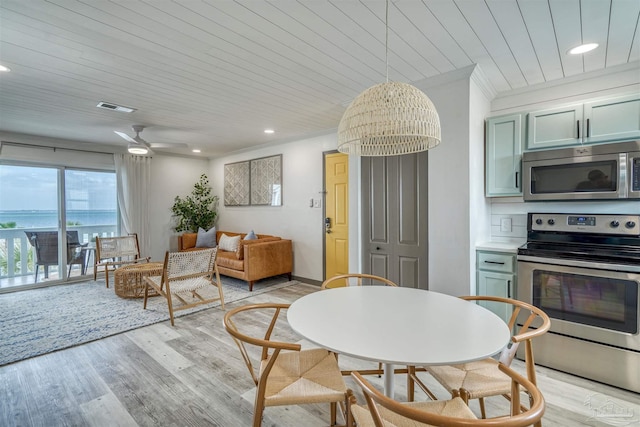 kitchen featuring crown molding, appliances with stainless steel finishes, light hardwood / wood-style flooring, pendant lighting, and ceiling fan with notable chandelier