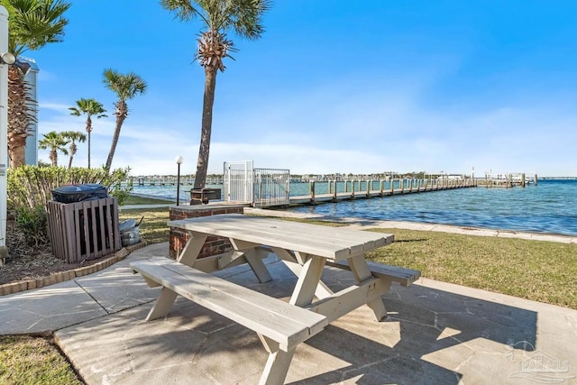 view of community featuring a water view, a lawn, and a patio area