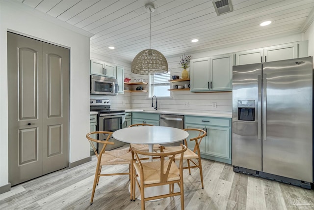 kitchen with stainless steel appliances, light hardwood / wood-style floors, sink, ornamental molding, and pendant lighting