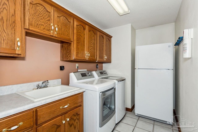 clothes washing area with cabinets, a textured ceiling, sink, light tile patterned floors, and washing machine and dryer