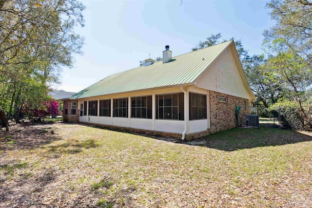 view of side of property with central AC unit, a sunroom, and a lawn