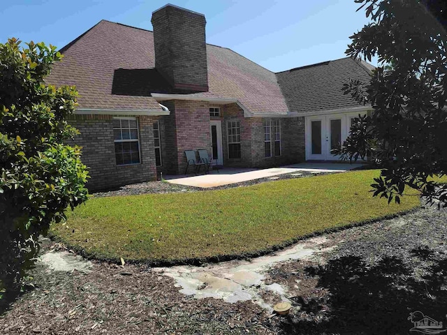 rear view of house with a patio area, a yard, brick siding, and french doors