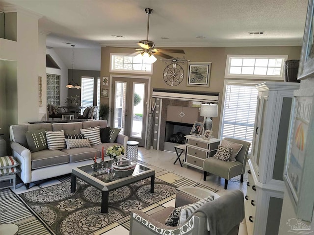 living room featuring a textured ceiling, plenty of natural light, a tile fireplace, and visible vents