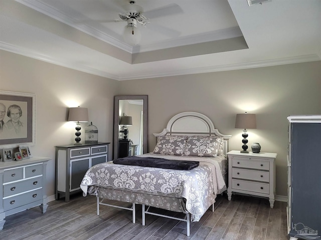 bedroom with a tray ceiling, wood finished floors, and baseboards