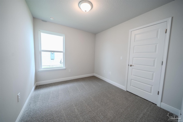 unfurnished room with carpet flooring and baseboards