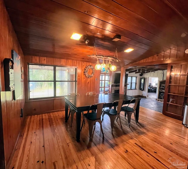 dining area featuring wood ceiling, wood-type flooring, wooden walls, and vaulted ceiling