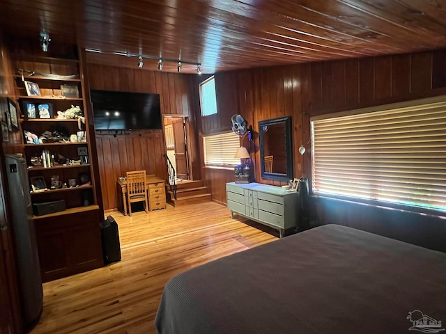 bedroom featuring wood walls, track lighting, hardwood / wood-style floors, and wooden ceiling