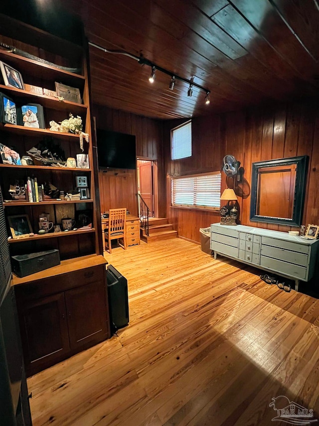 interior space with light hardwood / wood-style floors, rail lighting, wooden walls, and wooden ceiling