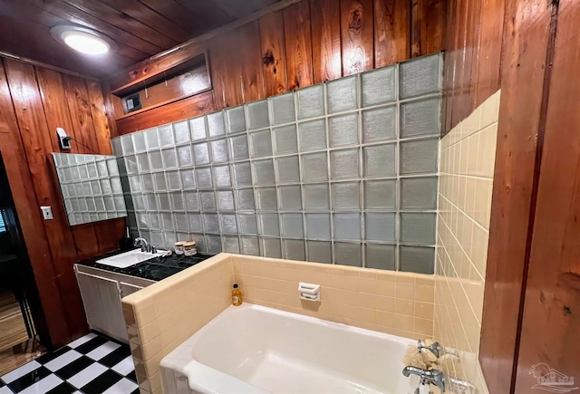 bathroom with wood walls, a washtub, and sink