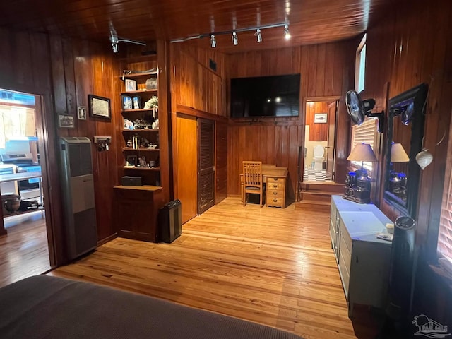 interior space with wood walls, wood ceiling, rail lighting, and light hardwood / wood-style flooring