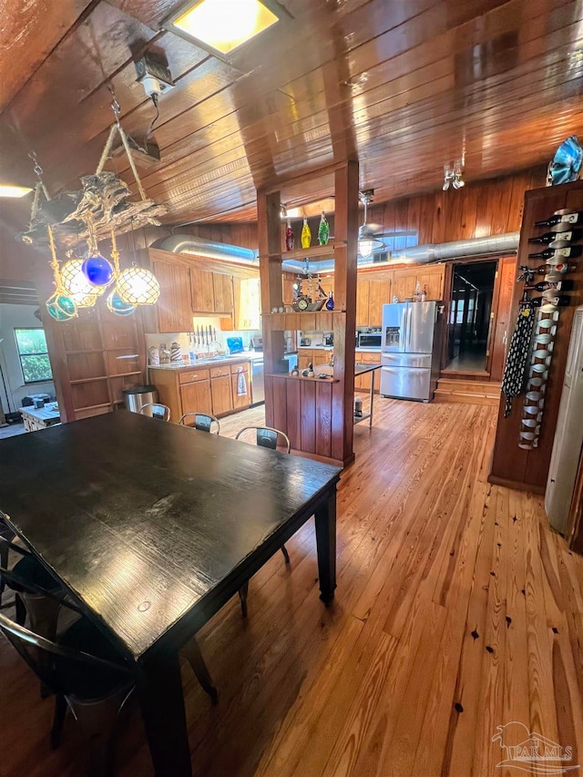 dining area featuring wooden ceiling, wood-type flooring, wooden walls, and lofted ceiling