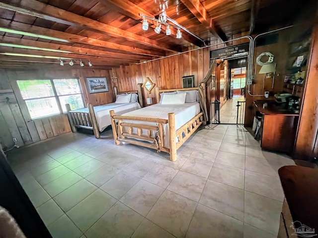 bedroom with wood walls, wood ceiling, light tile patterned floors, and beam ceiling