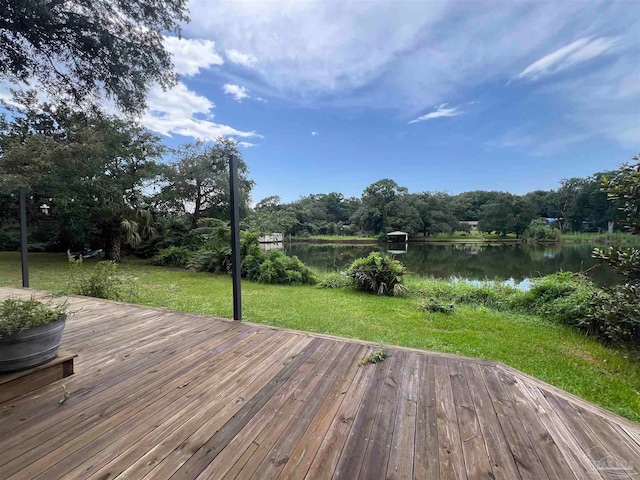 wooden deck with a water view and a lawn