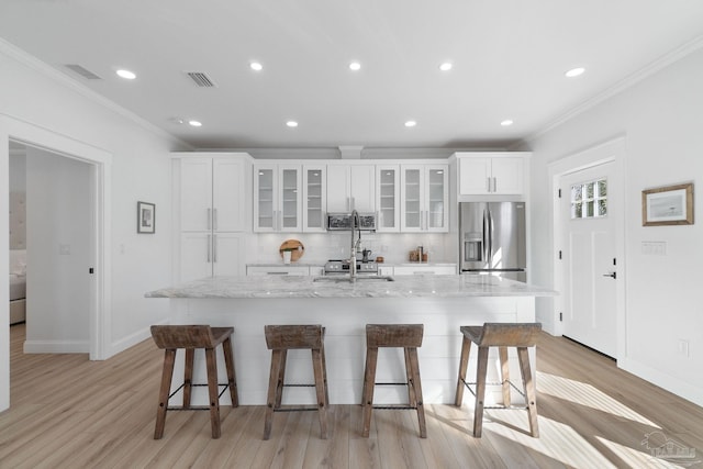 kitchen with visible vents, a breakfast bar, a large island, stainless steel fridge, and tasteful backsplash