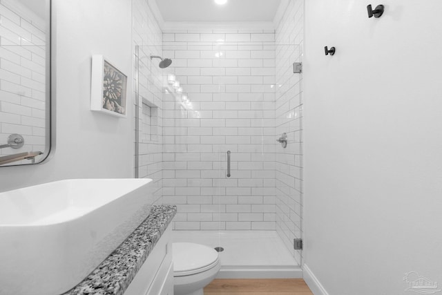 full bath featuring a shower stall, toilet, wood finished floors, and baseboards