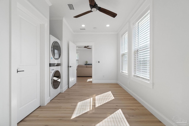 laundry area with light wood finished floors, visible vents, ornamental molding, and stacked washer and dryer