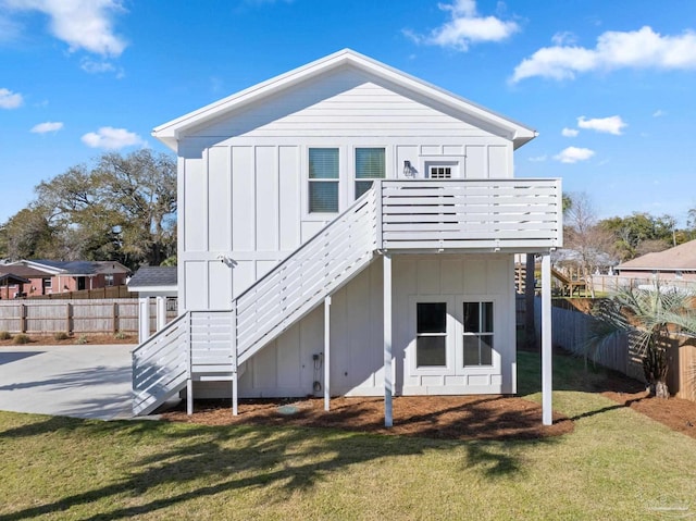 rear view of house with stairway, a yard, board and batten siding, and a fenced backyard