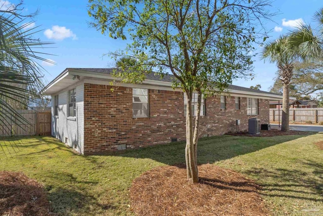 view of side of home featuring crawl space, brick siding, a lawn, and fence