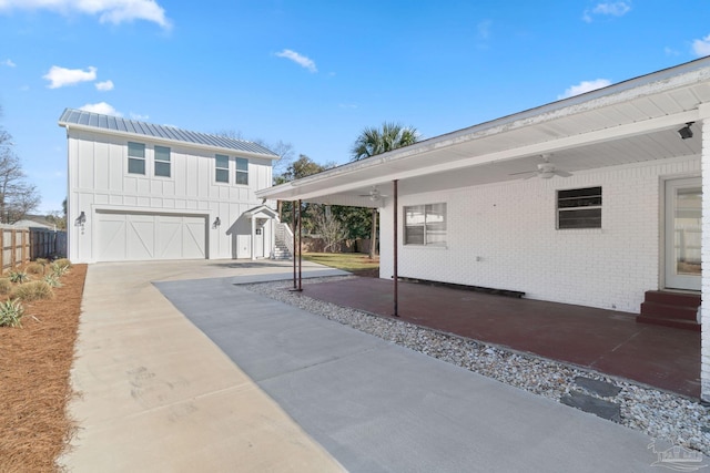 exterior space with fence, a ceiling fan, driveway, board and batten siding, and brick siding