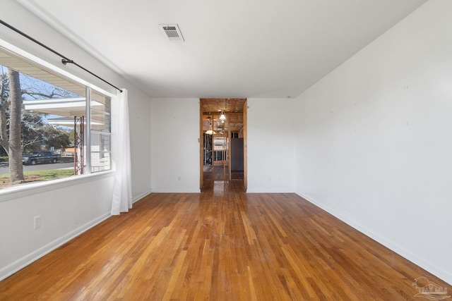 spare room with visible vents, baseboards, and wood finished floors