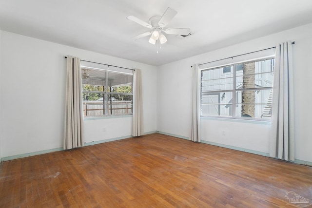 unfurnished room with baseboards, wood-type flooring, visible vents, and ceiling fan