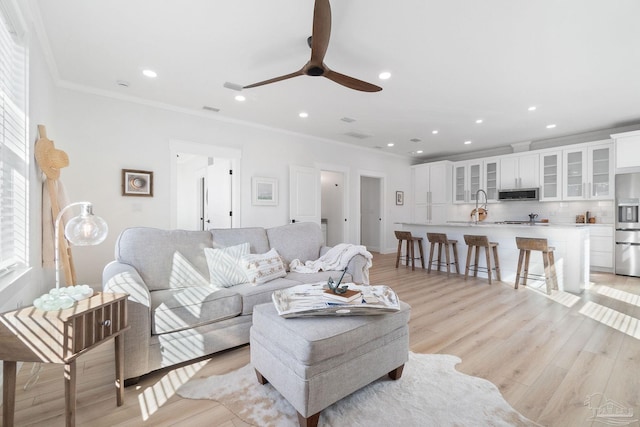 living room featuring recessed lighting, visible vents, light wood-style floors, and ornamental molding