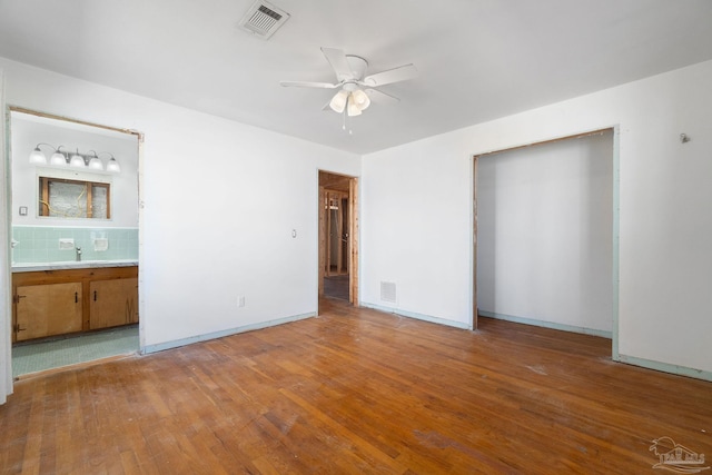 unfurnished bedroom with visible vents, baseboards, and hardwood / wood-style flooring