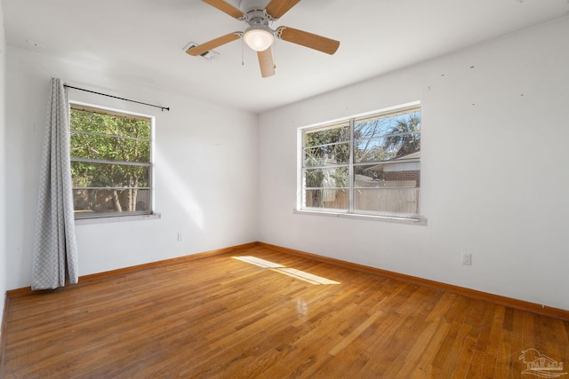 empty room with a wealth of natural light, baseboards, and hardwood / wood-style flooring