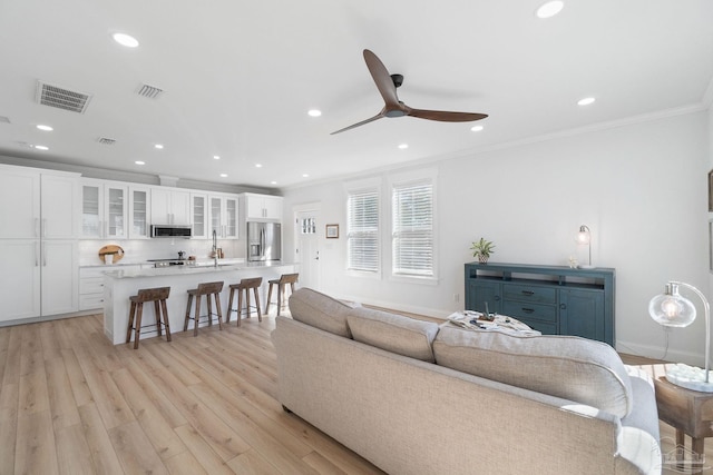 living room featuring visible vents, recessed lighting, light wood-style floors, crown molding, and ceiling fan