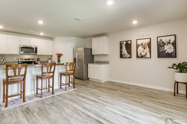 3488 Fallschase Blvd, Pensacola, FL 32526 - kitchen featuring stainless steel appliances, a breakfast bar, light wood-style flooring, white cabinets, and recessed lighting