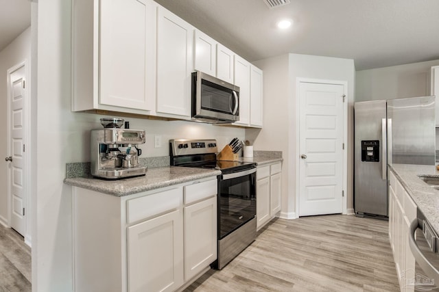 3488 Fallschase Blvd, Pensacola, FL 32526 - kitchen with stainless steel appliances, light wood finished floors, white cabinets, light stone counters, and recessed lighting