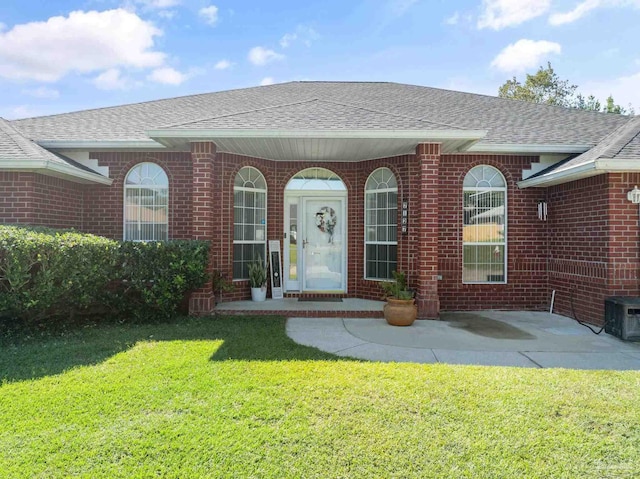 entrance to property with a lawn and a patio area