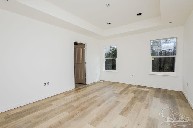 spare room with light wood-style floors, baseboards, a tray ceiling, and recessed lighting