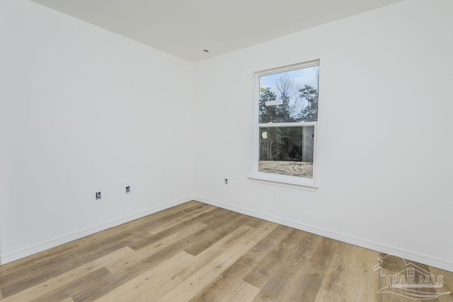 spare room with baseboards and wood finished floors