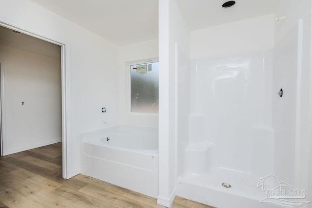 bathroom with a bath, a shower, and wood finished floors