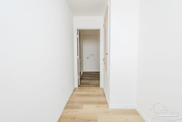 hall with light wood-type flooring and baseboards