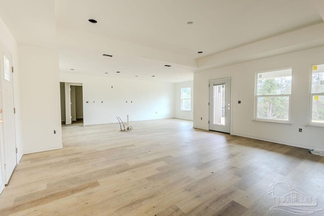 unfurnished living room with light wood finished floors, a raised ceiling, and visible vents