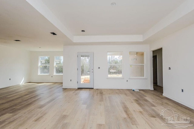 interior space with light wood-style flooring, visible vents, and a raised ceiling